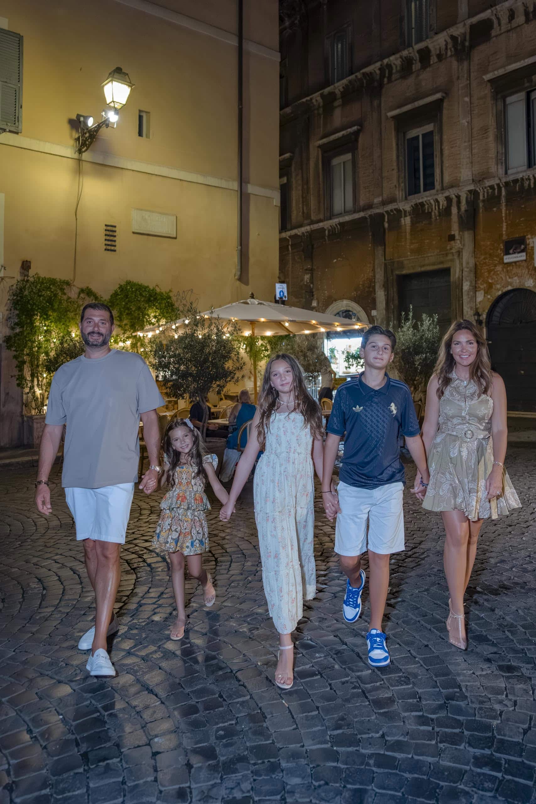 Family of five walking cobblestone Rome street - families photography in Rome by Finzi